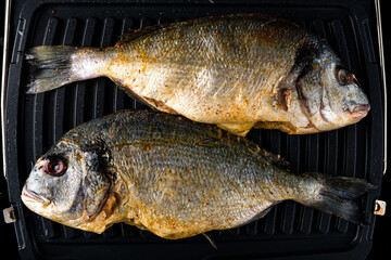Presentation of fresh wild sea bream on grill pan ready to cook