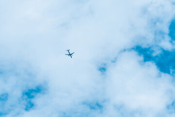 The plane flies in a big blue sky with white clouds background