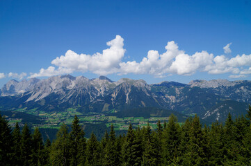 picturesque alpine panorama with a vast alpine valley of the Dachstein-Schladming region in the Austrian Alps against the blue sky with white fluffy clouds (Austria)