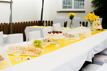 Garden party or wedding table with chair and flowers. White tablecloth and yellow decoration.