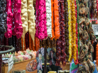 Close-up of colorful Churchkhela on the counter of the southern market. Traditional Georgian homemade sweet. Consists of various juices: grape, granulated, raspberry; nuts and fruits. 