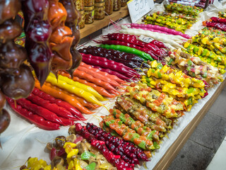 Close-up of a multi-colored Churchkhela on a market counter. Traditional Georgian homemade sweet. Consists of various juices, nuts, fruits. Tied with a thread. Vegetarian dessert. Horizontally