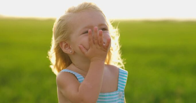 Ni&ntilde;a peque&ntilde;a adorable enviando beso al aire. Verano. Viento. C&aacute;mara lenta.