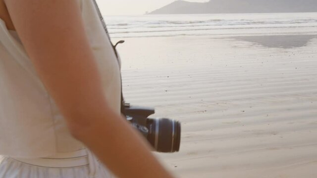 Detail image of woman walking with camera at Balneário Camboriú beach, Brazil.