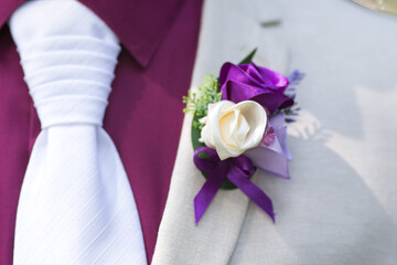 Purple wedding boutonniere flower on groom suit and tie. 