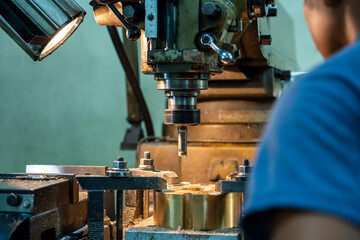 The machine operator drilling the hole on metal plate with NC milling machine.