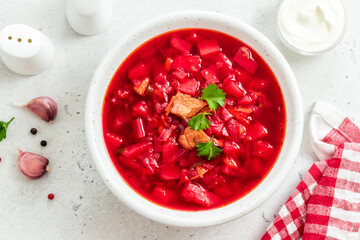 Classic vegetable borscht with parsley sour cream on light background. Top view, copy space.