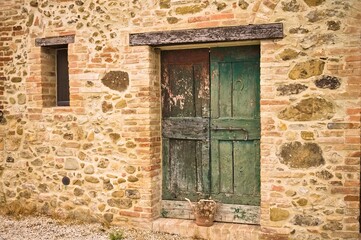 Fototapeta na wymiar A rustic wooden green door in a stone cottage in the Italian countryside (Umbria, Italy, Europe)
