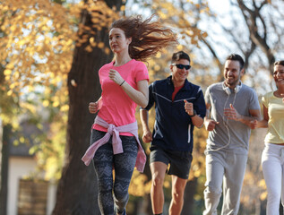 Red hair female in casual sport outfit jogging with her friends at city park.