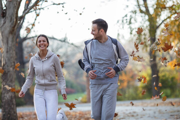 A couple of young friends enjoys an invigorating jog in the park during a crisp autumn afternoon,...