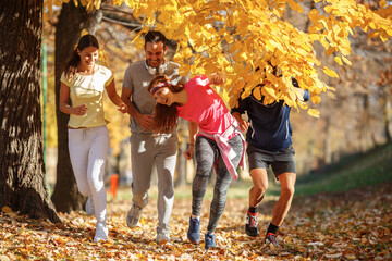 A group of young friends enjoys an invigorating jog in the park during a crisp autumn afternoon,...