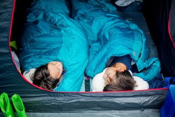 Two children, preteen boys, sleeping in sleeping bags in a tent on a vacation in Norway, wild...