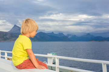Fototapeta na wymiar Child, cute boy, looking at the mountains from a ferry in Nortern Norway on his way
