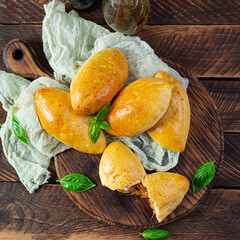 Traditional Russian cabbage pies on wooden background. Baked homemade pirozhki with cabbage. Top view