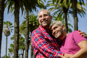Happy boyfriends hugging near palms