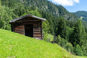 Traditional hay barn on a green meadow in the Tyrolian Alps in Austria on a sunny summer day