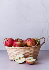 A basket with red apples on a wooden background. Sliced apples.