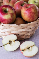 A basket with red apples on a wooden background. Sliced apples.
