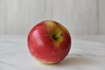 One red apple on the table. Light background.