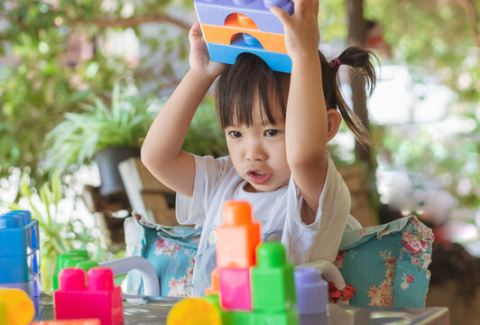 Portrait image of 3-4 toddler kid. Happy Asian child girl playing the plastic block toys. Learning and education concept. Smiling little baby.