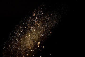 Dust and wood chips on a black background. Dirt particles fly in the air. Layout for design. Some...