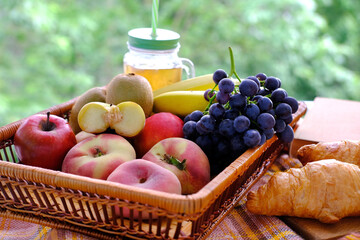 beautiful summer still life, fruits, grapes, peaches, apples, croissants, green trees in the background, concept picnic in nature, summer vacation, healthy eating