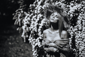 Contrasting black and white portrait of a sexy glamorous girl in a hat and dress in nature. With film grain, noise