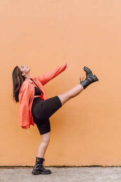 Energetic woman doing kick near painted wall