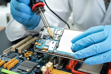 E-waste, technician repairing inside of hard disk by soldering iron. Integrated Circuit. the...