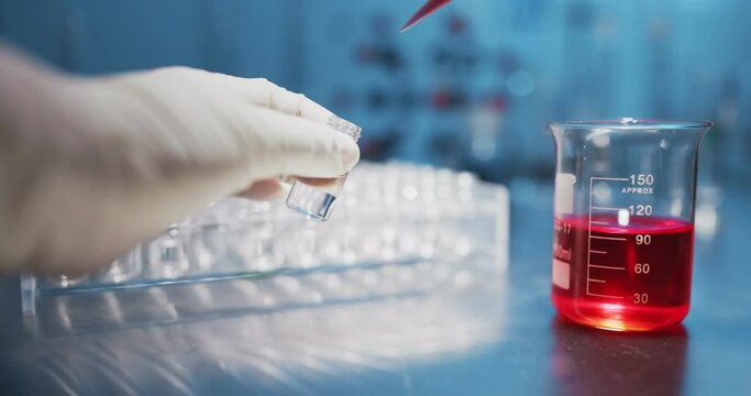 Scientist hand holding reagent bottle with chemical in laboratory.