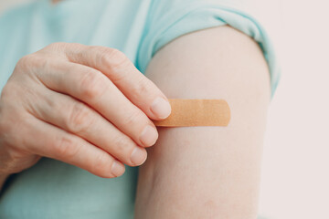 Vaccination elderly woman in doctor office with adhesive covid-19 vaccine plaster