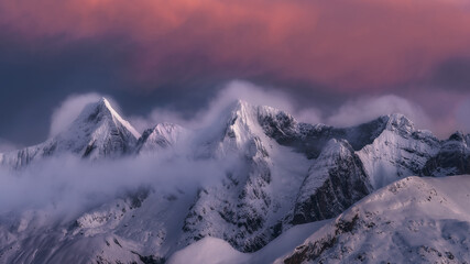 Landscape of snowy mountains covered by clouds