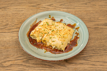 portion of pasta cannelloni stuffed with Cantabrian hake stew with grated cheese baked gratin with soy sauce