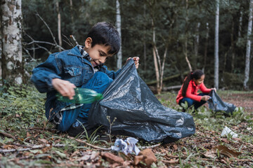 Ethnic children collecting garbage from land in forest