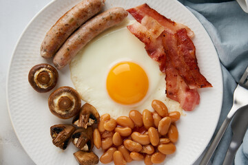 Horizontal closeup of rustic keto diet meal. Traditional english breakfast. Fried eggs, bacon, beans, mushrooms, sausages. Top view, copy space. Nutritious english cuisine