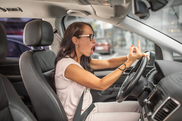 Female angry driver showing middle finger while driving in a parking lot