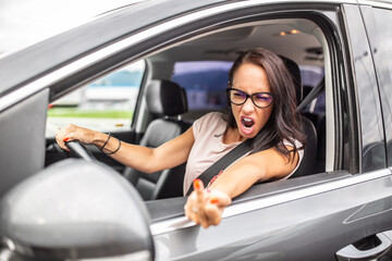 Naklejka premium Raging female driver shows middle finger into a rear mirror during a rush hour traffic congestion