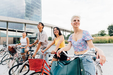 Group multiethnic friends posing outdoor riding bicycle enjoying sustainable alternative...
