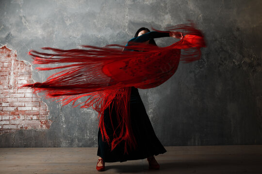 Young adult spanish woman dancing flamenco on gray vintage studio background