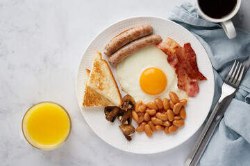 Horizontal top view of typical delicious english cuisine food. English morning breakfast. Mushrooms, egg yolks, bacon, beans, toasts, coffee, orange juice. Light background, copy space