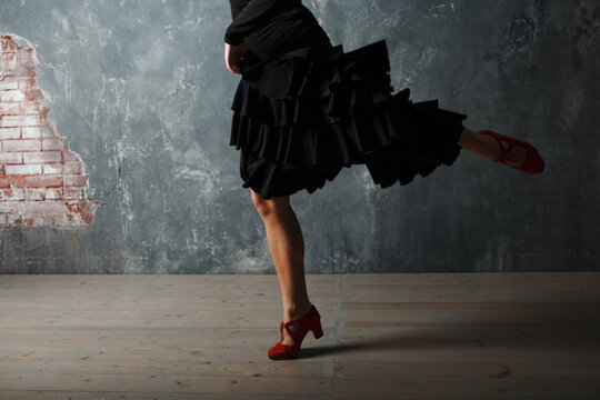 Young adult spanish woman dancing flamenco on gray vintage studio background