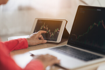 Senior woman is checking Bitcoin price chart on digital exchange on tablet