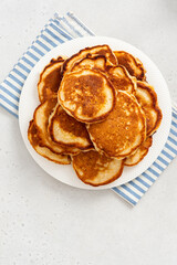 Homemade pancakes in a white plate on a gray concrete background top view.  Copy space for text. Tasty breakfast