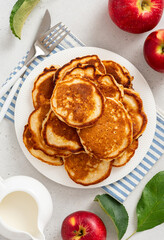 Homemade apple pancakes in a white plate on a gray concrete background top view. Tasty breakfast