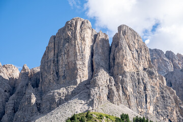 Fototapeta premium Alta Badia (Dolomiti) - August: Beautiful summer mountain view of Passo Sella and high peak Sassopiatto and Sassolungo, Langkofel, Dolomiti, Sella group. Green meadows and pastures, alpine dolomites