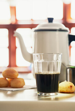 Copo de caf&eacute; com bule e p&atilde;es ao fundo