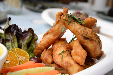 Battered fish fillets in a plate decorated with fruits and vegetables.