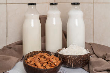 Homemade almond and coconut milk and bowls with the ingredients in a kitchen.