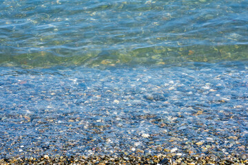 Background of wet pebbles washed by a sea wave