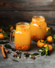 Autumn drink on a wooden background. Sea buckthorn tea with tangerines. A warming berry drink. Hot berry tea with cinnamon and anise.